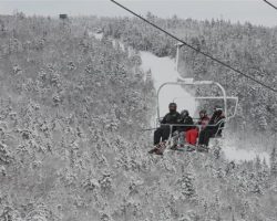 A family enjoys the ride in the Straight Brook Chairlift in the snow-covered landscape creating a holiday scene A family enjoys the ride in the Straight Brook Chairlift in the snow-covered landscape creating a holiday scene