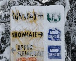 A snow-covered trail sign directs skiers from atop the East Chairlift A snow-covered trail sign directs skiers from atop the East Chairlift