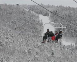A family enjoys the ride in the Straight Brook Chairlift in the snow-covered landscape creating a holiday scene A family enjoys the ride in the Straight Brook Chairlift in the snow-covered landscape creating a holiday scene