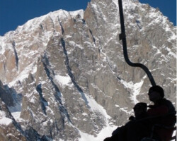Skiers in chairlift with Mont Blanc in background Skiers in chairlift with Mont Blanc in background